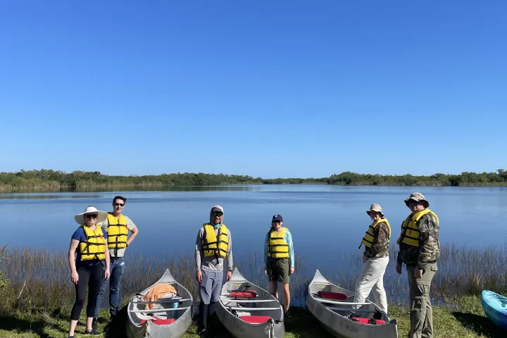 a group of people standing behind canoes