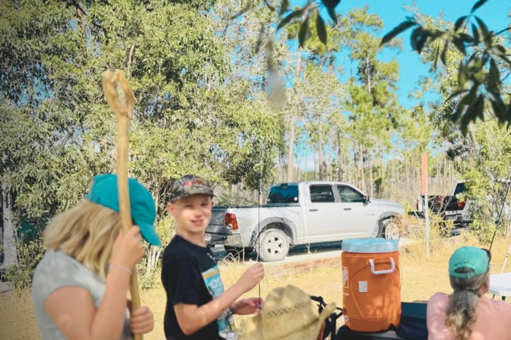 People sitting outdoors with a pickup truck and cooler nearby.
