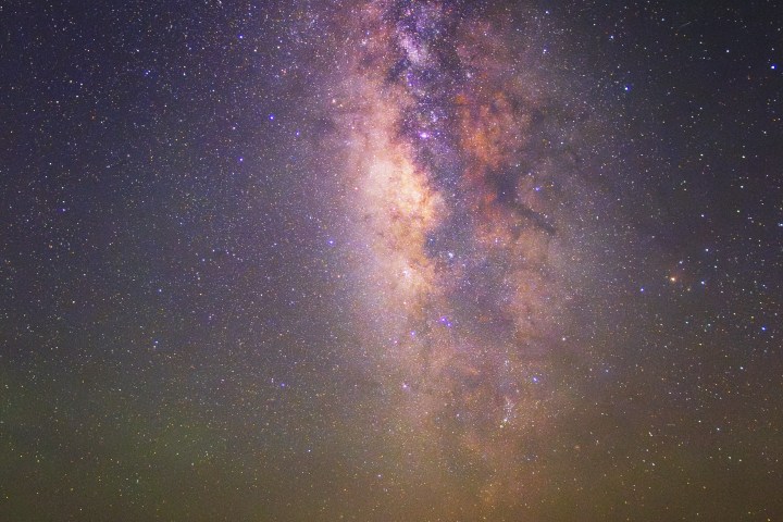 Starry night sky over an empty road with the Milky Way visible.